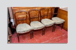 A set of four late 19th Century walnut dining chairs having a simple carved top and central rail,