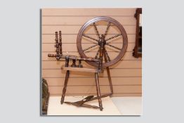 A late 19th Century oak spinning wheel having nicely turned spindles and supports, the spoked