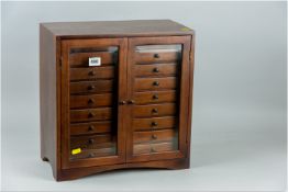 An eighteen drawer two door 20th Century teak collector's cabinet having twin bevelled glass