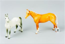 A Beswick pottery standing model of a palomino coloured horse, 8 x 10 ins (20 x 25.5 cms) along with