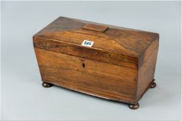 A Victorian sarcophagus shaped rosewood tea caddy set upon turned bun feet, the chamfered lid