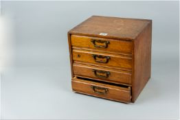 An oak collector's cabinet of four drawers with two sectional dividers, each having pierced brass