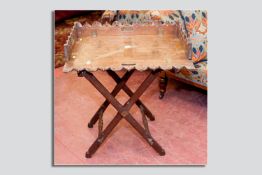A late 19th Century oak butler's tray and stand of Gothic form, the pierced and castellated tray