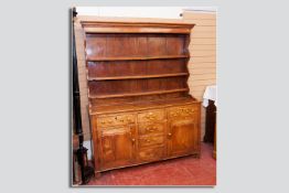 An 18th Century North Wales elm and fruitwood dresser having a moulded rack top with multi-shaped