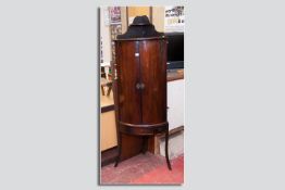 A Georgian mahogany bow fronted cabinet on stand, twin opening doors with shelved splatback above on