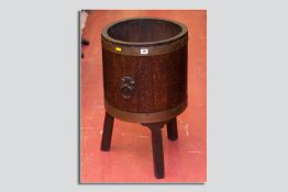 A good sized oak and brass banded barrel planter on three square supports
