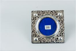 A square scrolled silver easel picture frame to take a circular picture 3.75 ins (9.5 cms) diam,