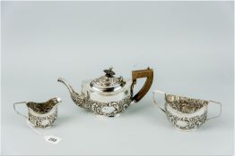 A three piece silver bachelor tea service, each piece of oval form with raised scrolled and floral