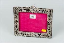 An oblong floral and scrolled patterned silver easel picture frame to take a picture 4.25 x 6 ins (
