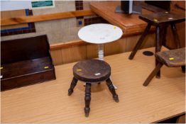 White painted cast iron tripod table of miniature form, 14 ins (35.5 cms) high along with a circular