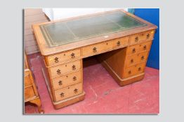 An oak twin pedestal desk with gilt tooled green leather top, a run of three drawers over two