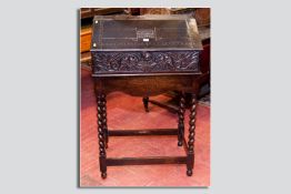An early 18th Century Bible box on later barley twist stand, the sloped fall with a central carved