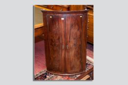 A Georgian mahogany two door corner cabinet, the doors with pagoda style escutcheons opening to