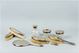 An eight piece silver/silver backed dressing table set of two pairs of brushes and a hand mirror