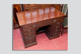 An ornately carved twin pedestal desk, oak top over twin drawers with twin banks of four drawers