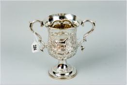 A silver twin handled trophy cup, uninscribed and having raised scroll work and an attractive