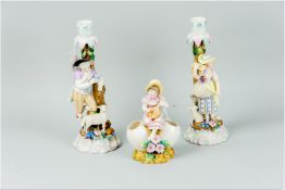 A pair of German porcelain candlesticks modelled in the form of a young man and young woman standing