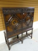 An early-twentieth century carved and stained raised cabinet with geometric panelling with floral
