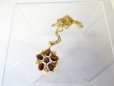 A 9ct yellow gold floral brooch set with garnets and pearls and on a 9ct gold fine necklace, 11.5gms