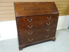 A Georgian mahogany fall-front bureau, of three long and two short drawers, the slope revealing an