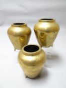 A Chinese trio of matching polished bronze vessels on three feet and each having a large elaborate