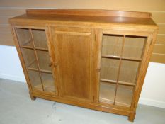 A light oak Brynmawr Furniture 'Gower Dwarf' rail-back triple bookcase having a pair of segmented