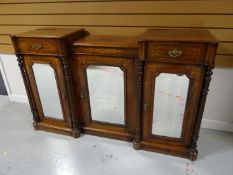 A late Victorian marquetry breakfront credenza, having a trio of mirrored doors interspersed with