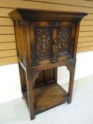 A dark wood Gothic- style raised cupboard with fall-front single door above a lower tier. 51 ins