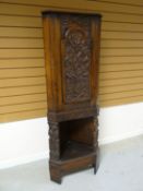An early-twentieth century standing corner cupboard, profusely carved with figures, flowers and