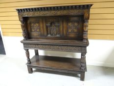 An antique-reproduction Jacobean-style court-cupboard with carved panels and friezes, and having