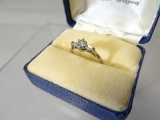 An 18ct white gold diamond ring with centre round cut stone in a six-claw setting with small diamond