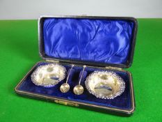 A cased pair of silver salts of circular form with raised decoration and gilt interiors, with