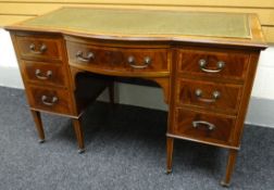 An Edwardian inlaid and crossbanded mahogany desk having a bowed centre drawer flanked by three