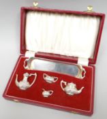 A cased silver five-piece miniature tea-set comprising long twin-handled tray, creamer, sucrier, tea