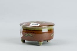 A David Frith circular trinket pot and cover on three feet, green celadon type and brown