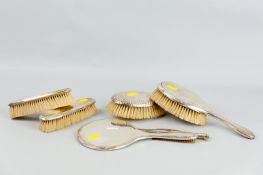A five piece silver dressing table set of hand mirror, oval hand brush, two narrow brushes and a