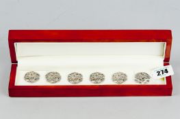 A cased set of six, possibly Continental silver, buttons of pierced serpent and dragon form
