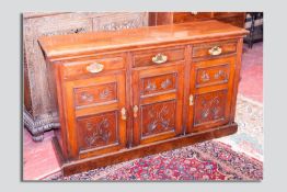An Edwardian mahogany sideboard base having three chamfered panel doors with brass swing handles and
