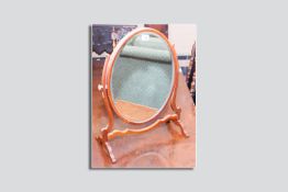 A 20th Century oval mahogany bevelled edge swing toilet mirror with shaped stretcher and supports on