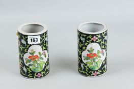 A pair of Famille Noire brush pots, twin quatrefoil panels decorated with flowers, an overall flower