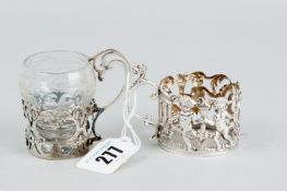 Two silver tody glass holders, one of cherubic design, Chester 1906, the other of scrolled and