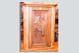 A small reproduction carved oak corner cupboard, the single opening door with inset carved panel
