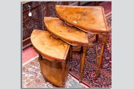 An attractive nest of three bow fronted walnut corner coffee tables, each having a curved shell