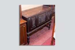 A carved oak dower chest on stand, a carved lidded top over three chamfered carved panels of a