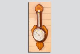 An Edwardian mahogany and inlaid aneroid barometer, the shaped banjo style wooden background