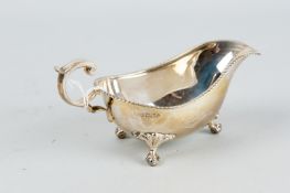 A silver cream boat with scrolled handle, three ball and claw supports with bird crest and gadrooned