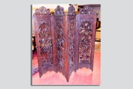 An excellent 20th Century hardwood four fold dressing screen having profusely pierced carved leaf
