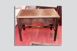 An early 20th Century carved oak side table/desk with brown leather insert top with carved edge,