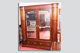 A late Victorian/early Edwardian ebony and mahogany two door mirrored wardrobe, a shaped crown