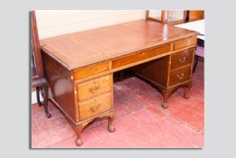 An early 20th Century oak and mahogany twin pedestal desk having a gilt tooled triple skiver top